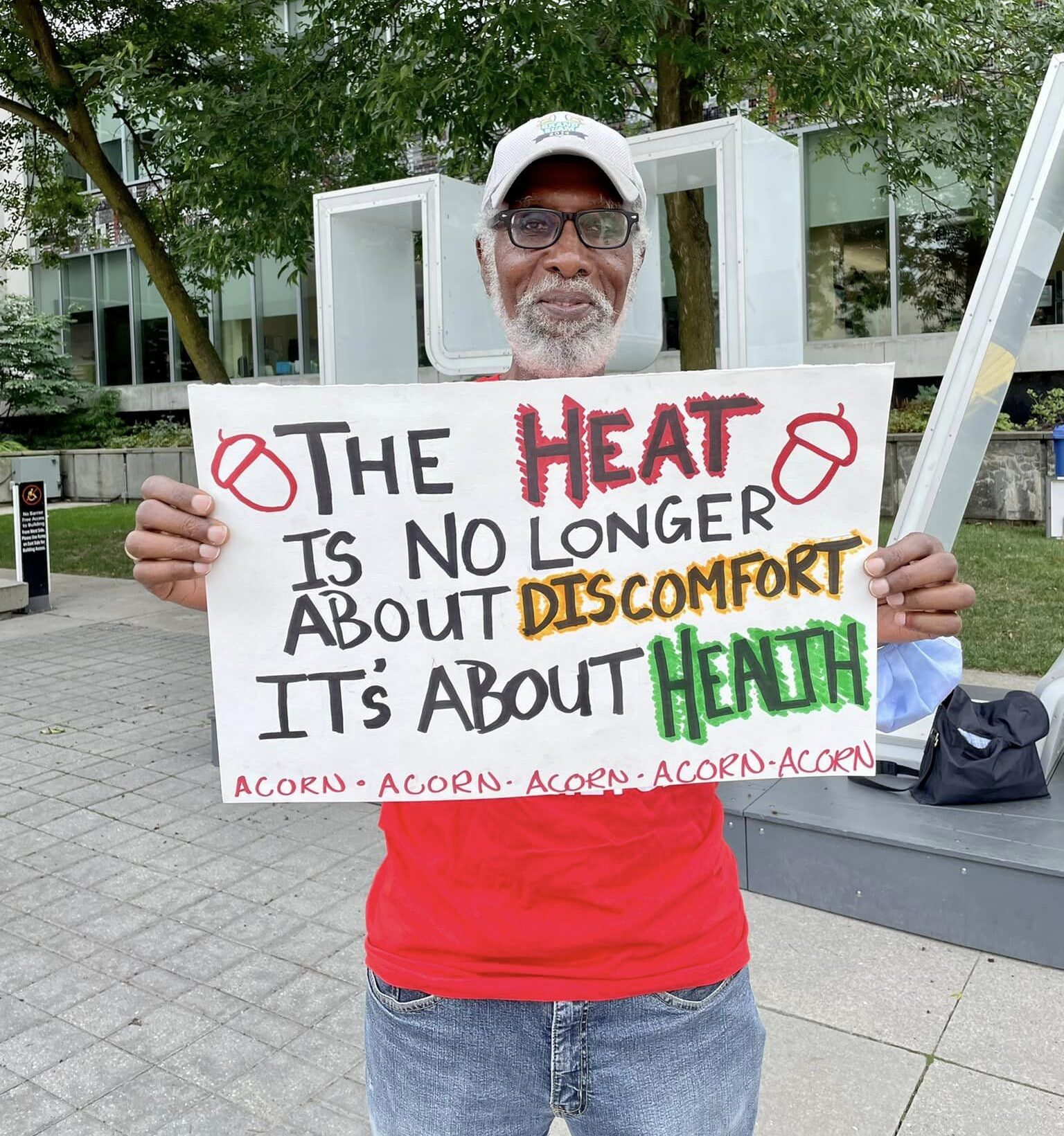 A man holds up a sign with The Heat is no longer about discomfort. It's about Health.Tenants from Canadian Apartment Properties REIT buildings in Ottawa vote to form an eco-tenant union through ACORN in their neighbourhood.
