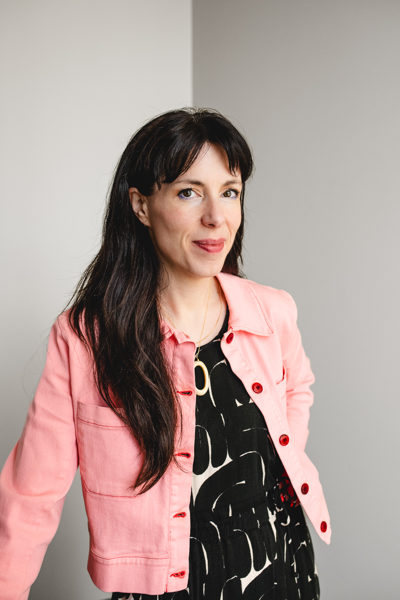 Photo de Maggie MacDonald, avec une œuvre d'art à l'arrière-plan représentant un lac, avec des montagnes nuageuses dans les gris et les bleus sombres.